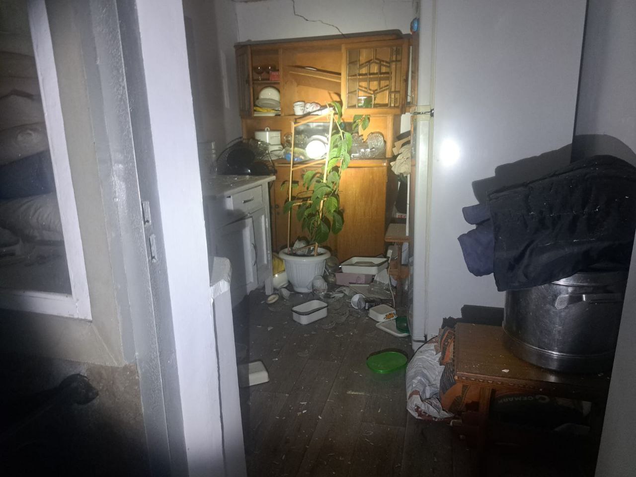 Понівечена кімната в будинку: речі попадали на підлогу, а на стіні - тріщина