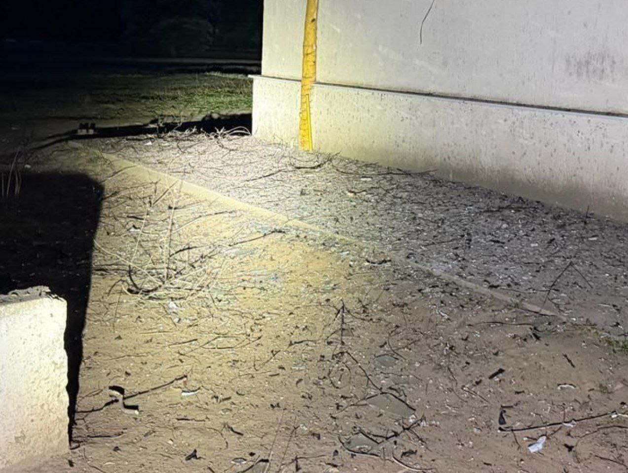 Земля поряд з понівеченою багатоповерхівкою усіяна уламками битого скла